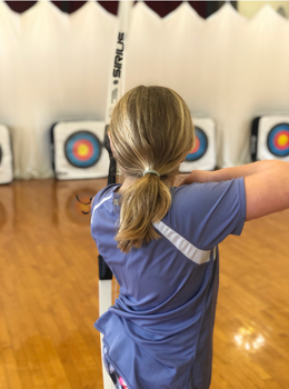 Girl aiming bow and arrow at targets.