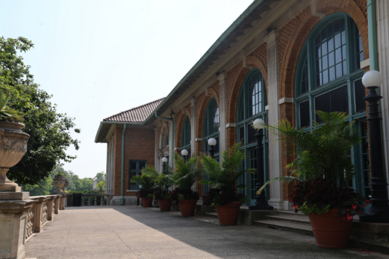 Exterior of brick building with arched windows and potted plants.