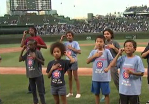 Children signing the national anthem at a Cubs game.
