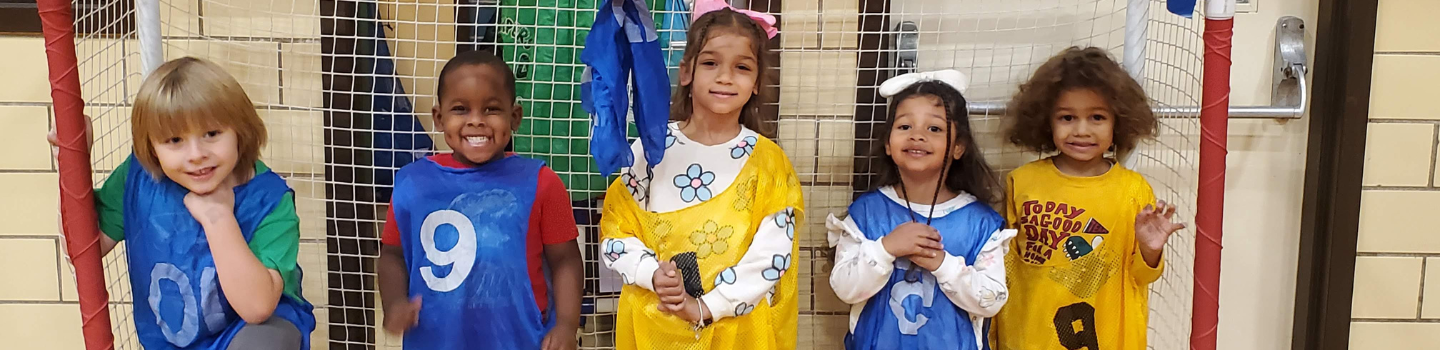 Five children in colorful clothes pose by a sports net.