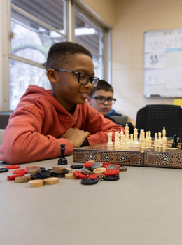 Boy smiles while playing chess.