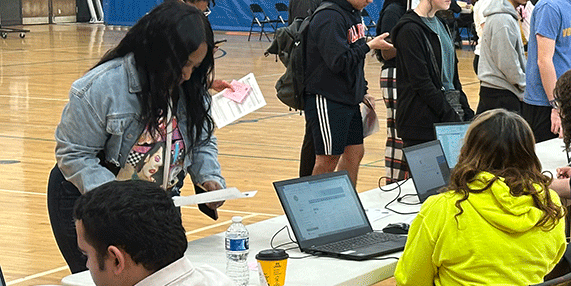 People are completing paperwork in a park gymnasium