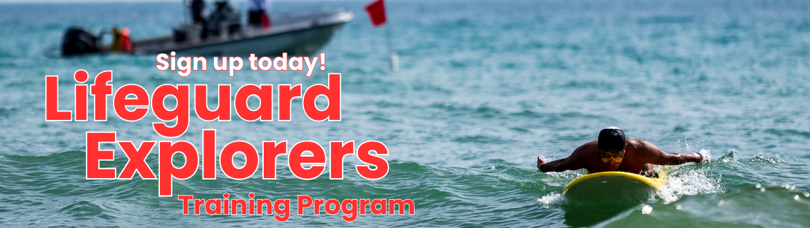 Lifeguard paddling a rescue board in the ocean.  A motorboat is in the background.