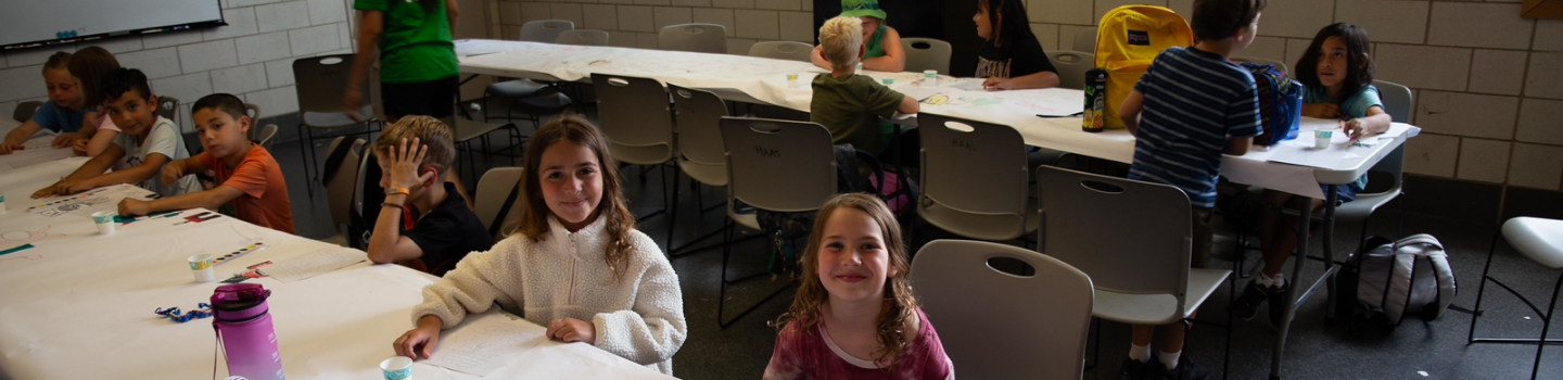 Children sit at tables creating art projects.