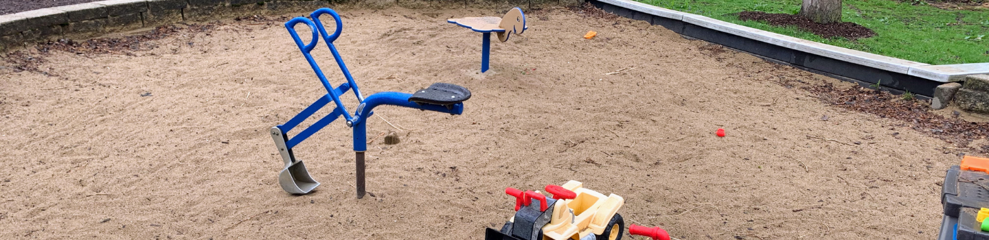 Sandbox with a blue digger and toy bulldozer.