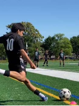 Soccer player kicks ball on field during game.