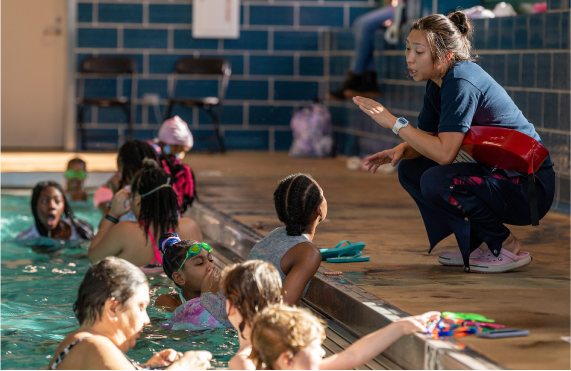A lifeguard talking to kids in a pool